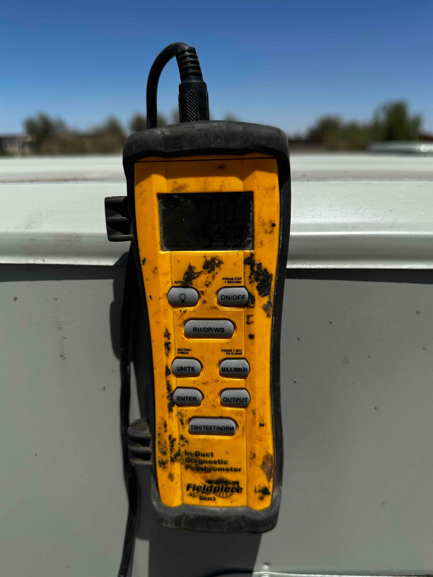 Digital hygrometer mounted on the unit during air-side checks; the display is not clearly readable in this photo.
