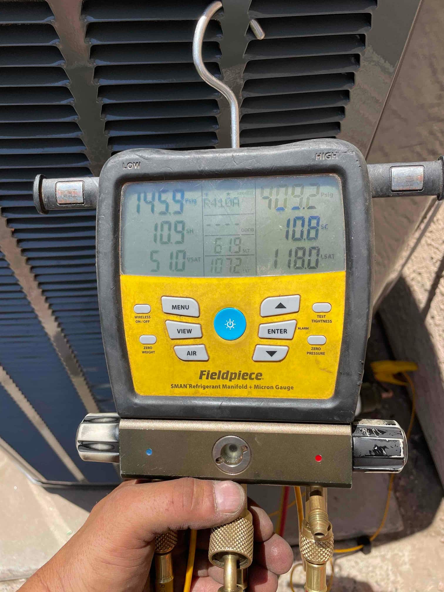 Digital manifold connected at the condenser shows operating pressures and calculated superheat and subcooling during system startup verification.