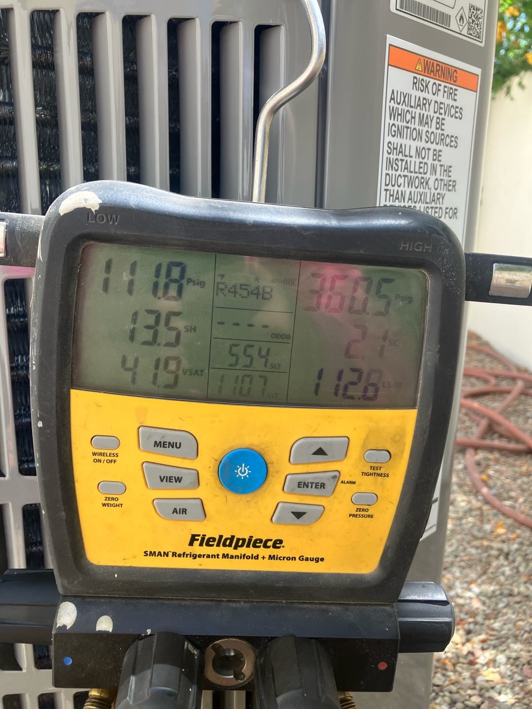 Digital manifold connected at the condenser shows system operating pressures while charging and tuning the new installation.