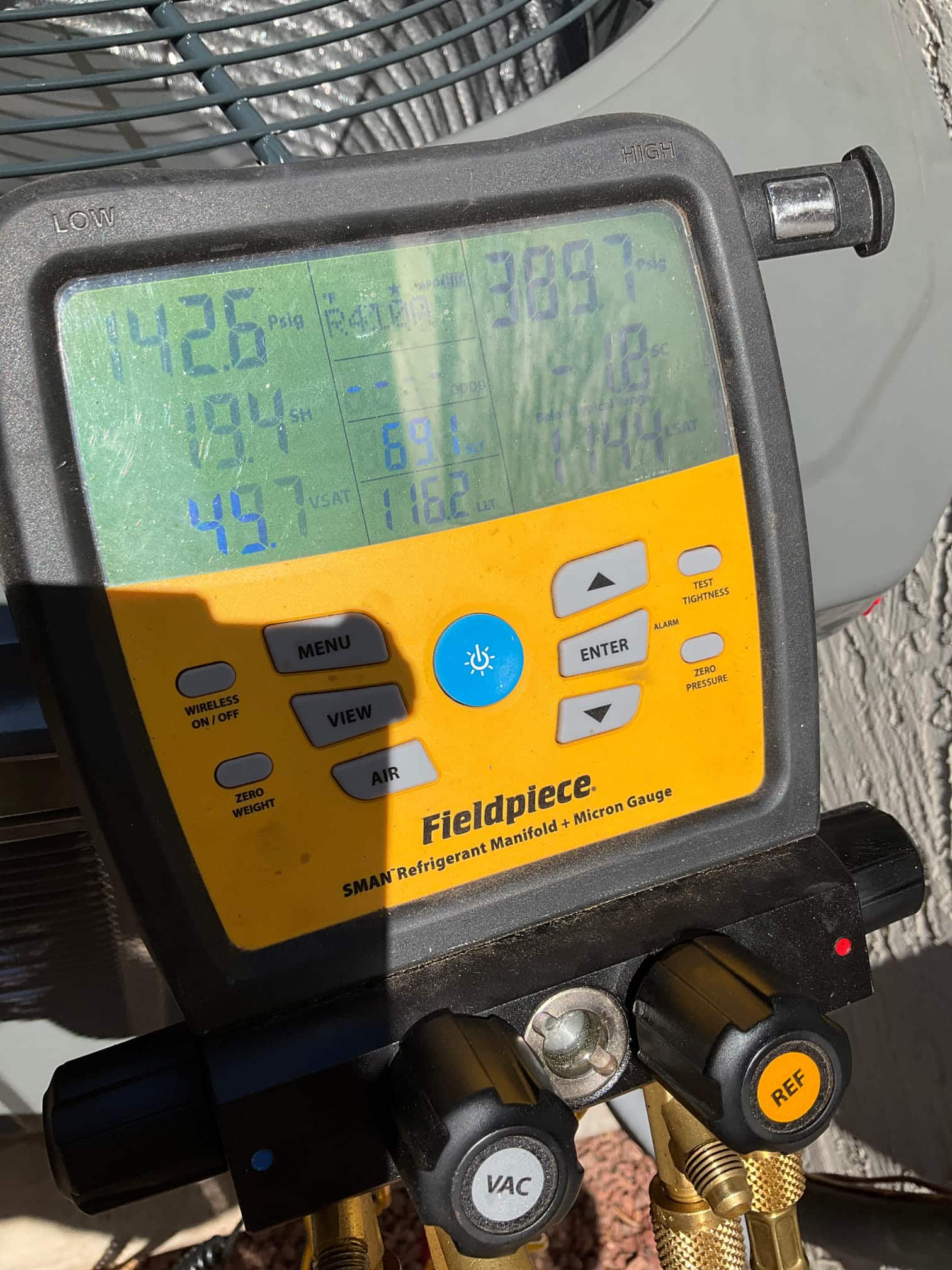Digital manifold connected at the outdoor unit shows operating pressures during startup, with distinct low and high side readings on the display.