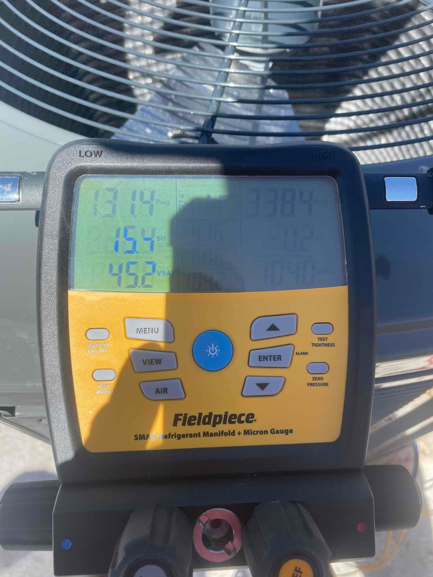 Digital manifold connected at the outdoor unit shows operating pressures with superheat and temperatures during system commissioning.