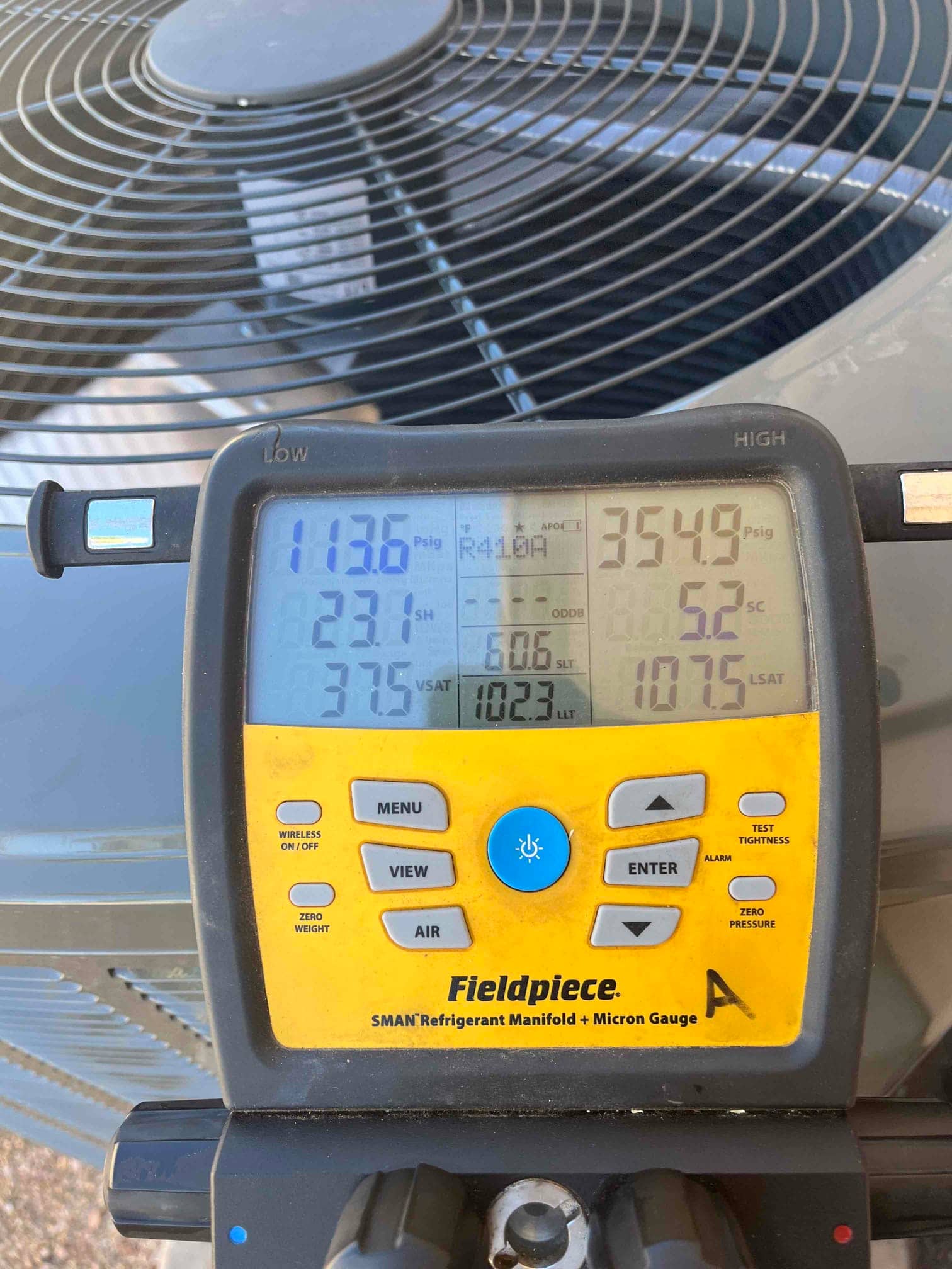Digital manifold connected to the outdoor unit shows system operating pressures with R-410A selected during commissioning.