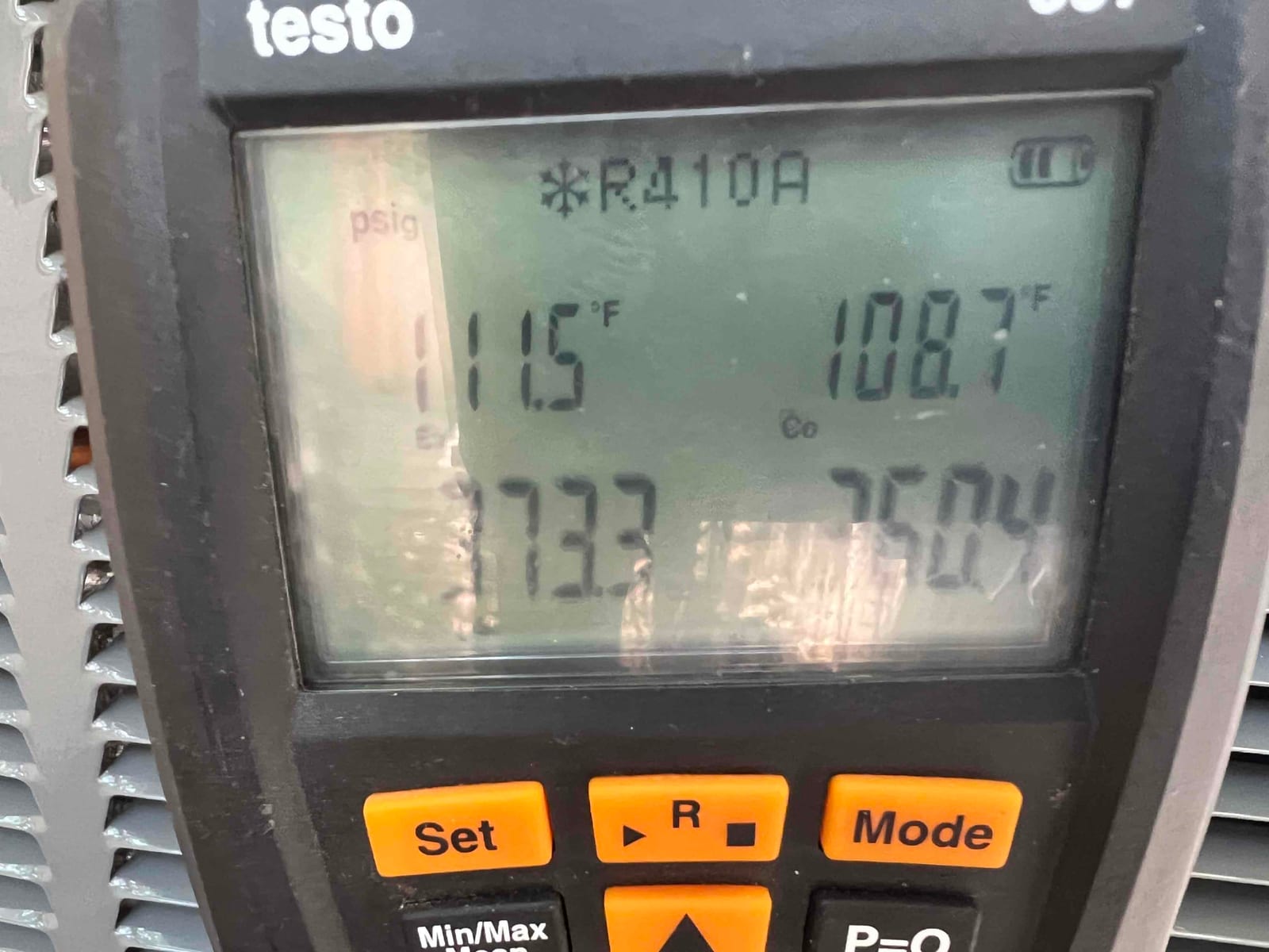 Digital manifold display during system operation showing refrigerant type R-410A and temperature readings on outdoor unit.