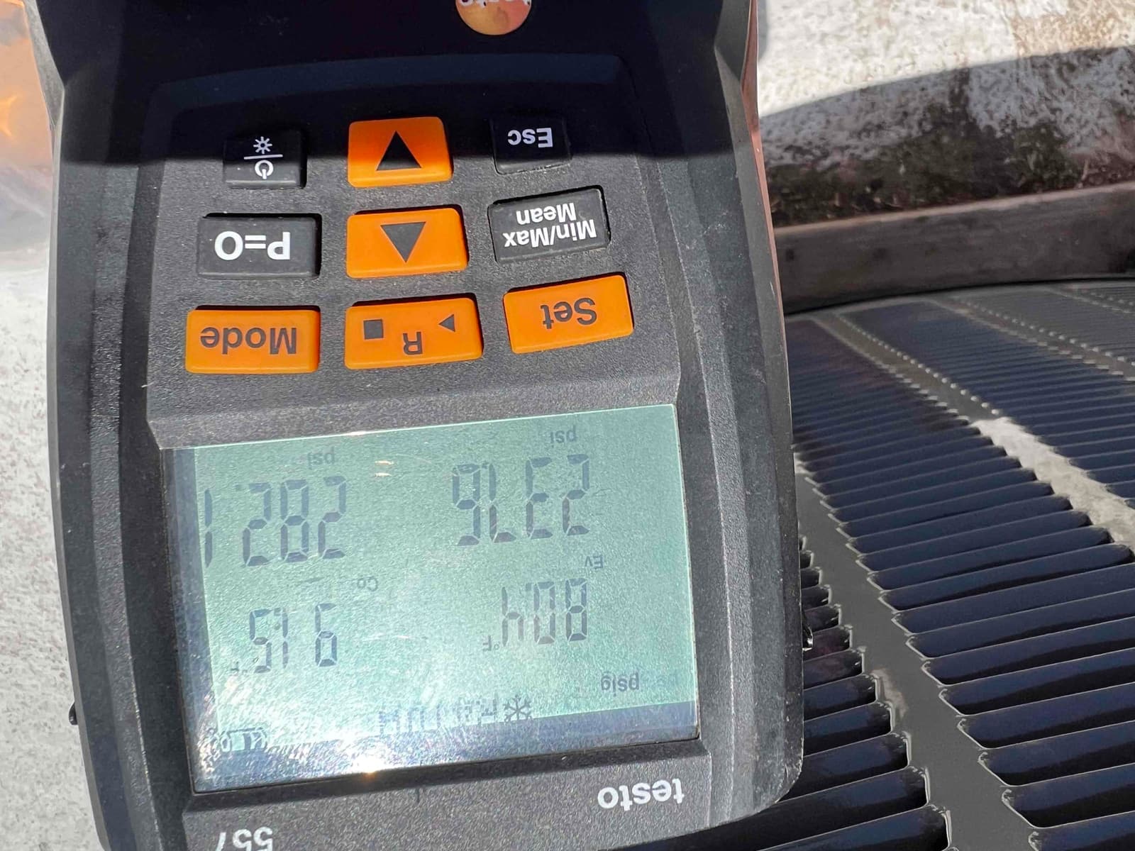 Digital manifold displays operating refrigerant pressures beside the outdoor condenser during system commissioning.