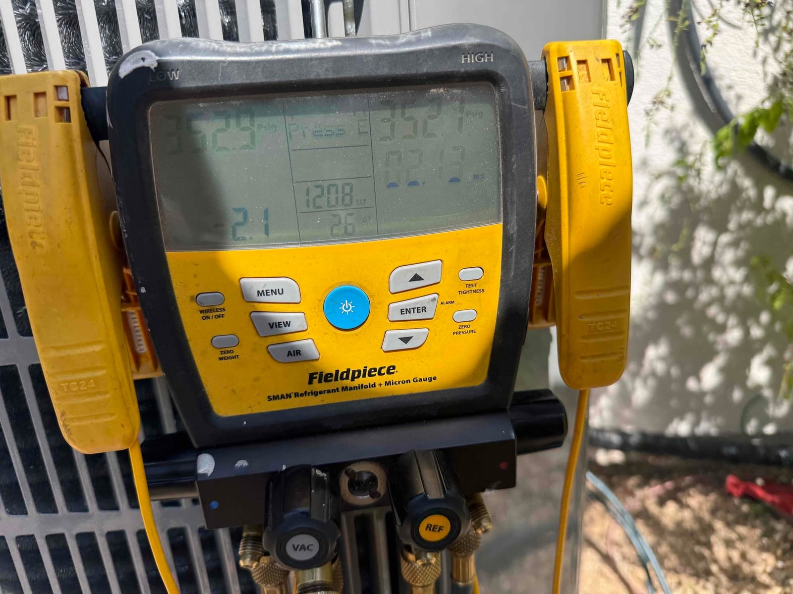 Digital manifold gauges display equal high pressure on both sides during a nitrogen pressure test at the outdoor unit.