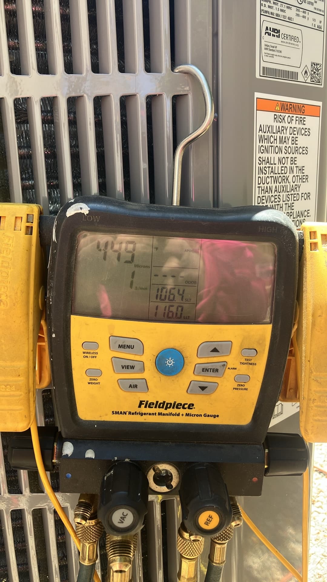 Digital manifold with micron gauge attached at the condenser shows a deep vacuum achieved during system evacuation.