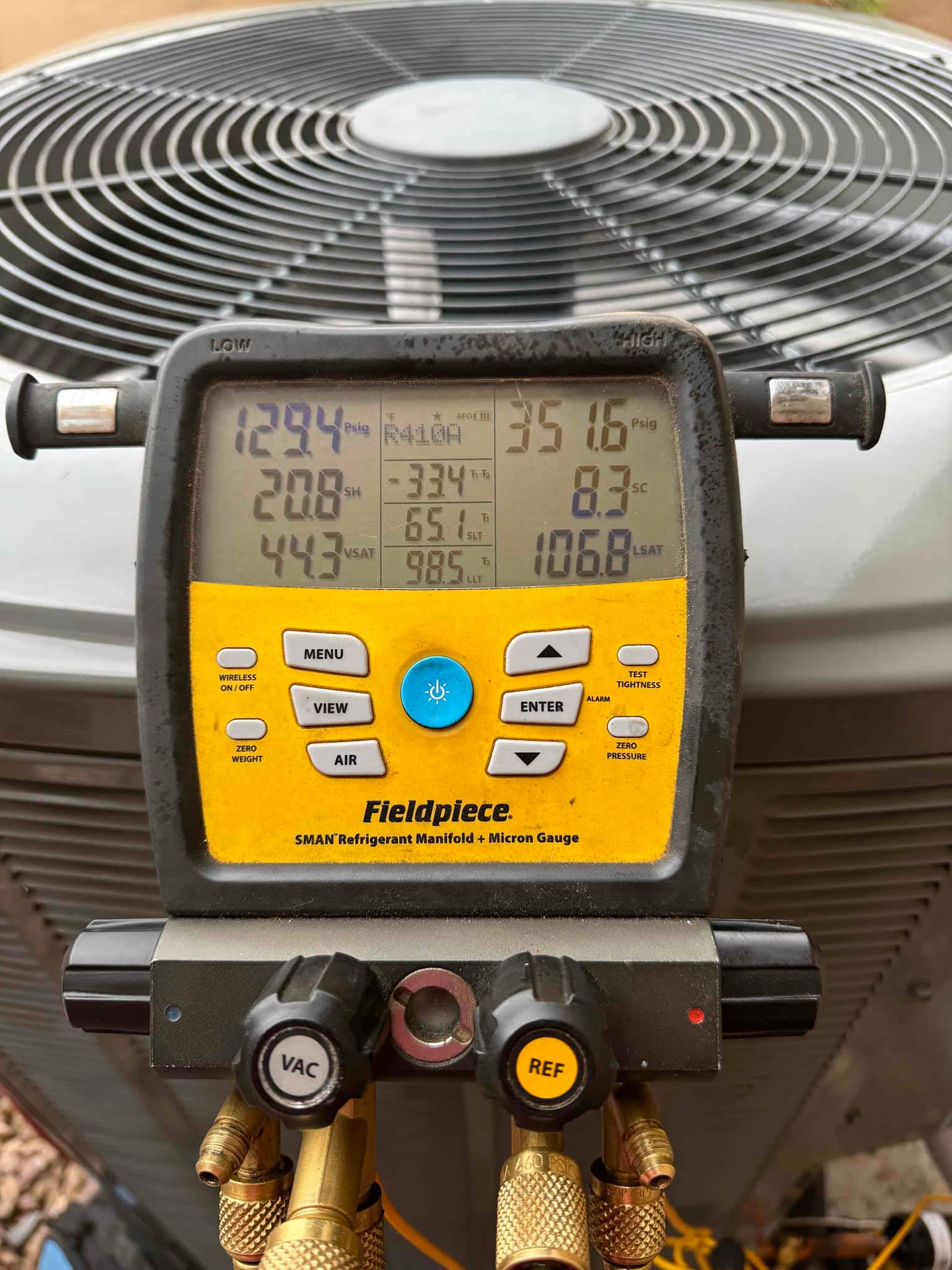 Digital manifold on the outdoor condenser shows operating pressures and temperatures during system commissioning.