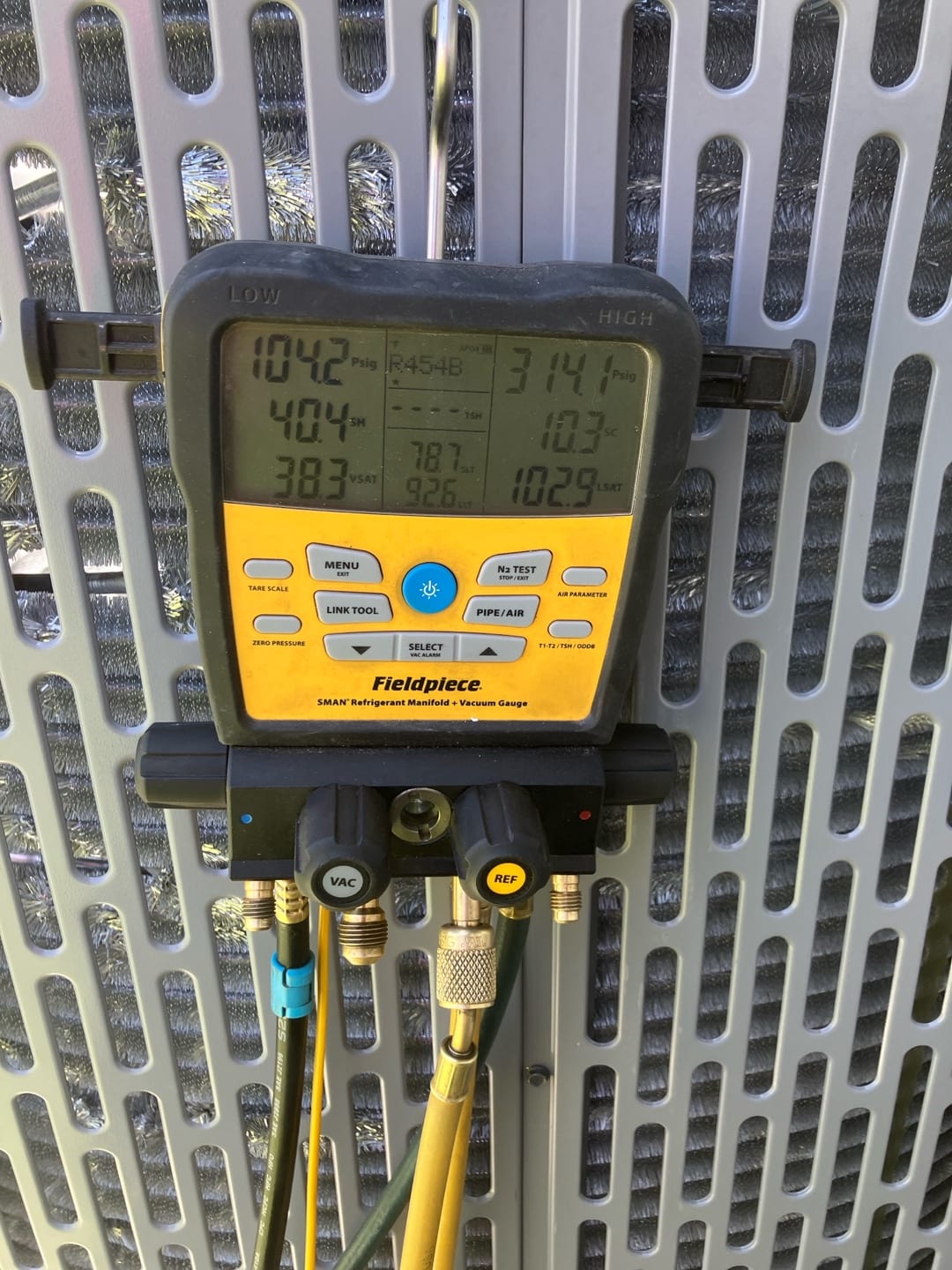 Digital manifold on outdoor unit displays operating pressures and temperatures during system commissioning.