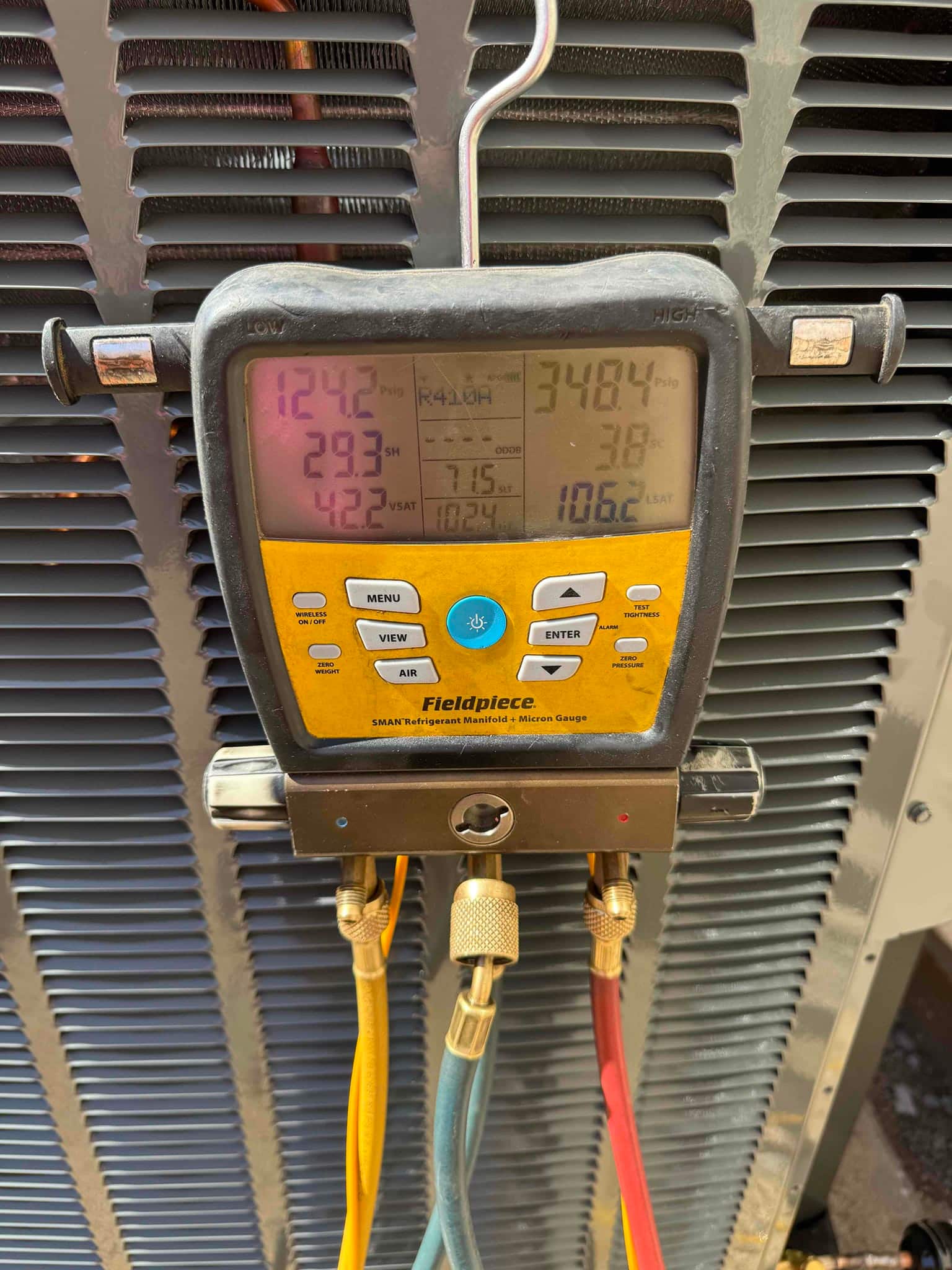 Digital manifold on the outdoor unit shows low side 124 PSI and high side 348 PSI during system operation.