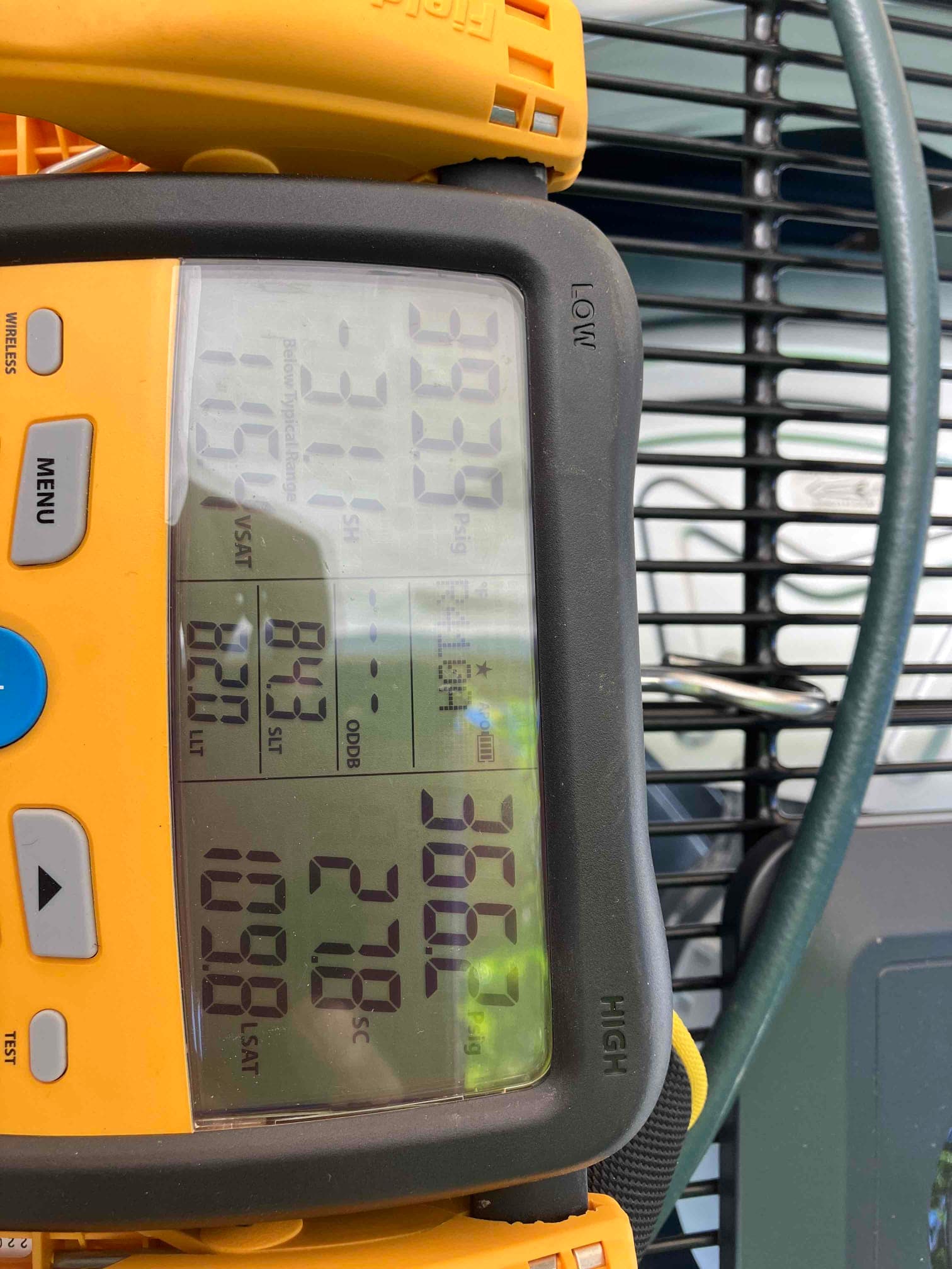 Digital manifold on the outdoor unit shows split operating pressures with superheat and subcooling during system commissioning.