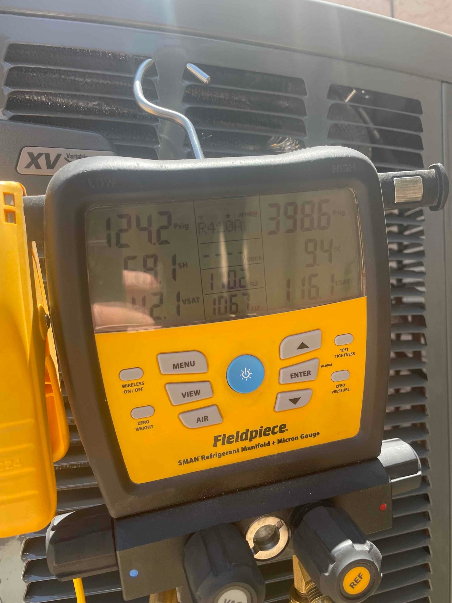 Digital manifold on the outdoor unit shows system operating pressures and calculated superheat and subcooling during commissioning.
