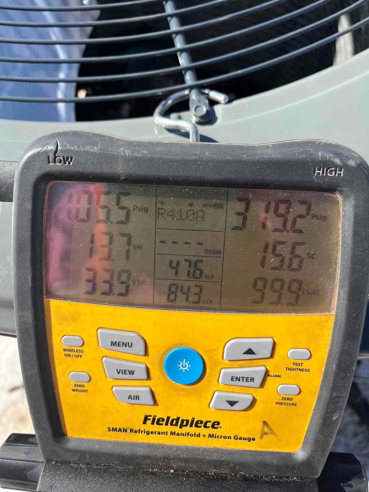Digital manifold shows operating pressures on an outdoor condenser during startup commissioning.