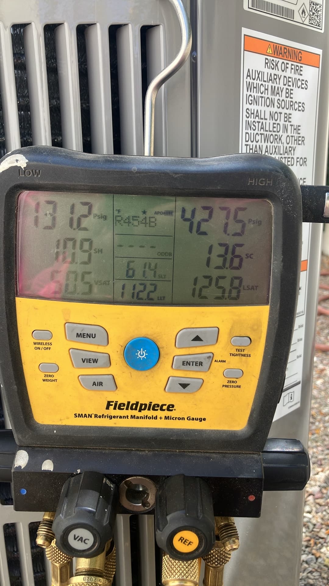 Digital manifold shows system operating pressures and temperatures during commissioning on the outdoor unit.