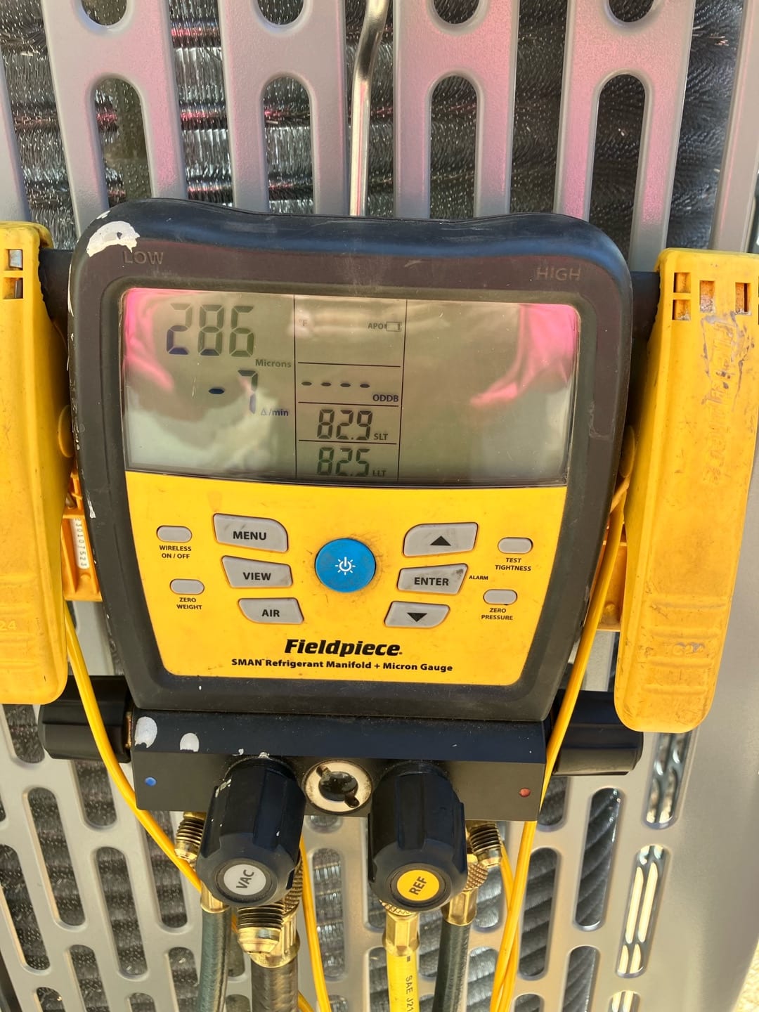 Digital micron gauge on the condenser shows 286 microns during evacuation, confirming a deep vacuum before refrigerant charging.