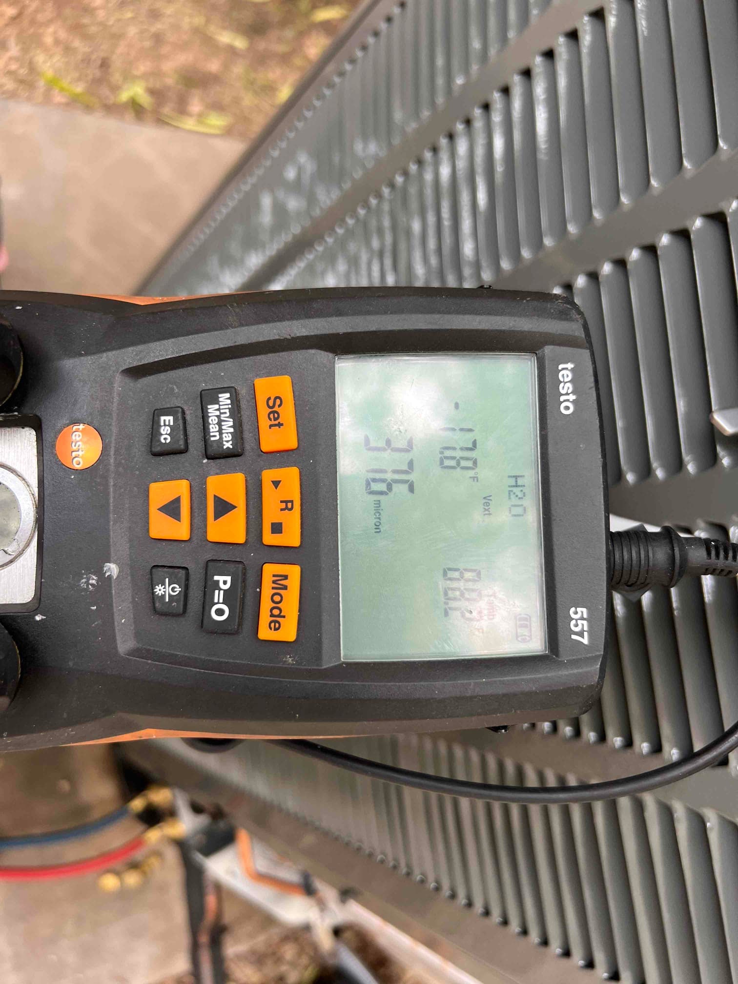 Digital micron gauge connected at the outdoor unit shows a deep vacuum achieved during system evacuation.