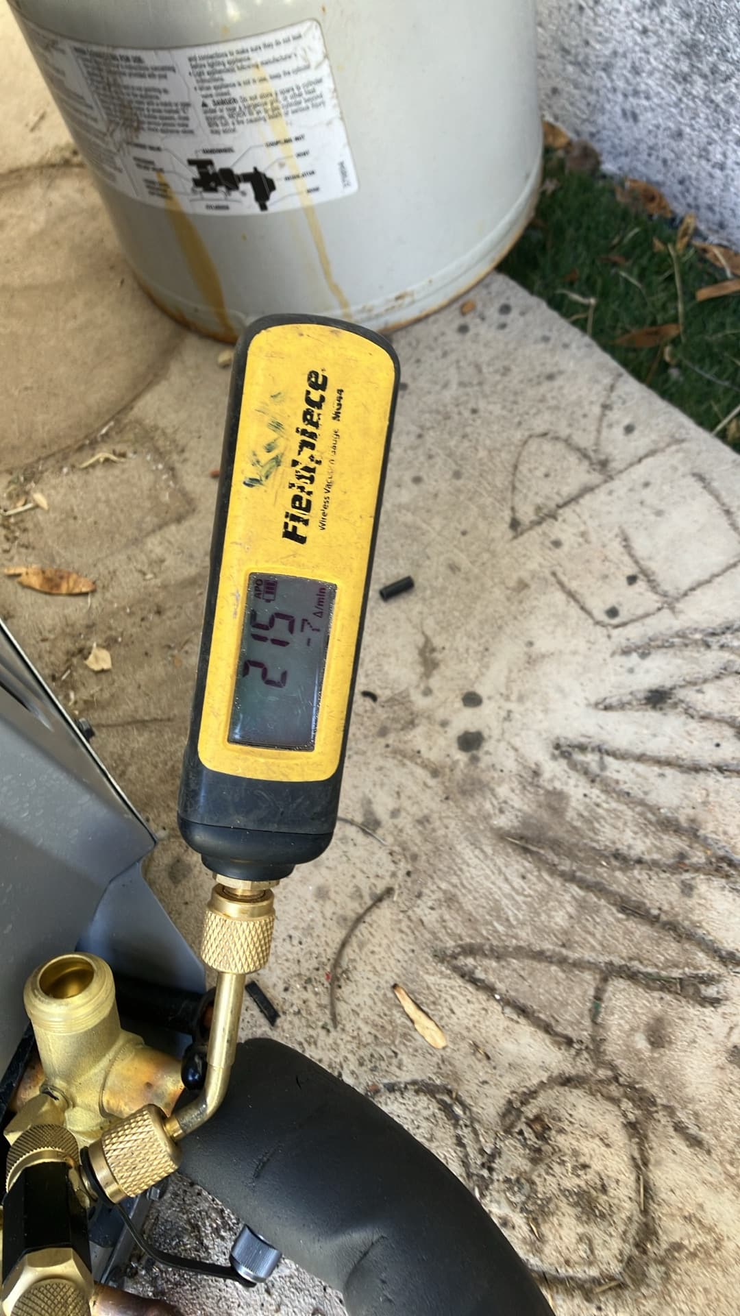 Digital micron gauge connected to the service port reads 215 microns, confirming a deep vacuum before refrigerant charging.