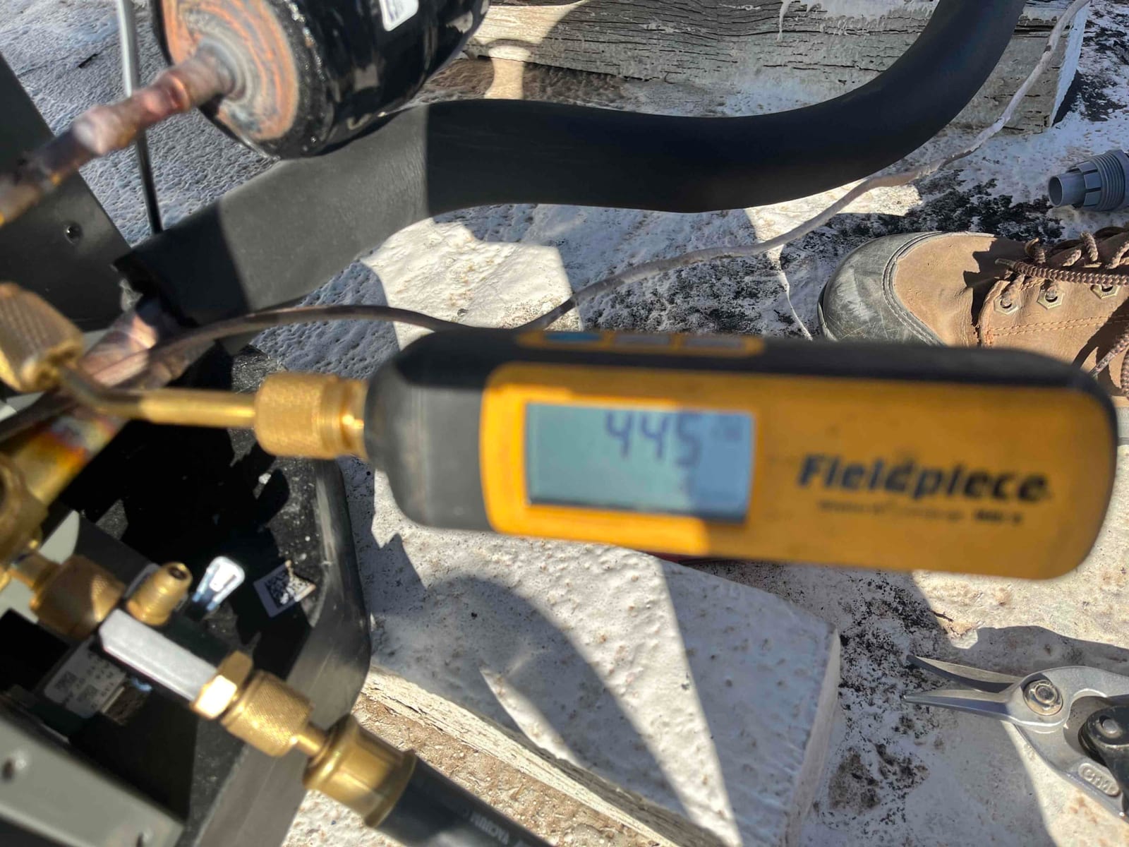 Digital micron gauge connected at the service port shows 445 microns during evacuation of the new heat pump system.