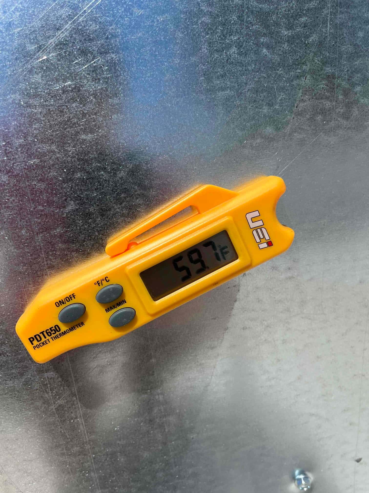 Digital pocket thermometer shows 59.7°F while measuring air temperature during supply air checkout on the new system.