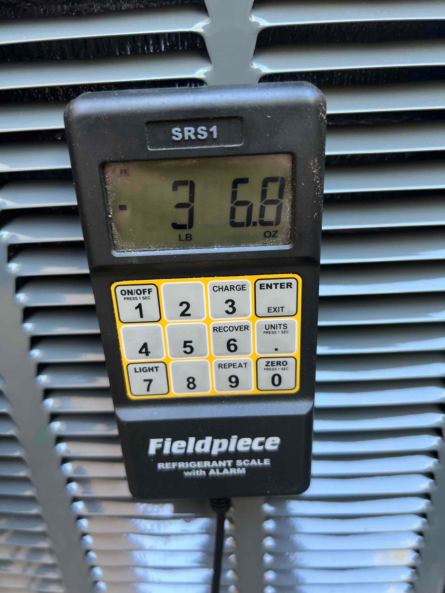 Digital refrigerant scale display shows 3 pounds 6.8 ounces during charging at the outdoor unit.