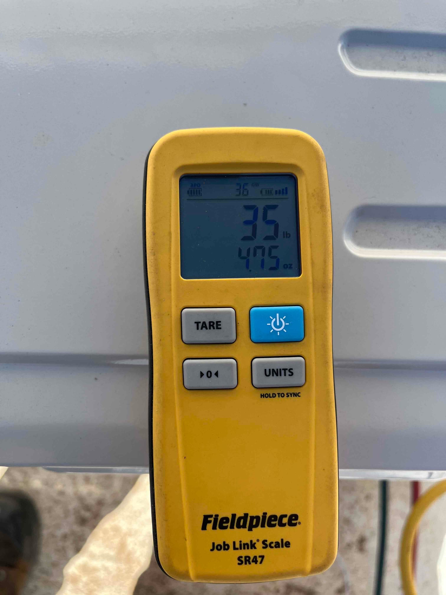 Digital refrigerant scale handheld display shows a reading of 35 pounds 4.75 ounces during charging setup.