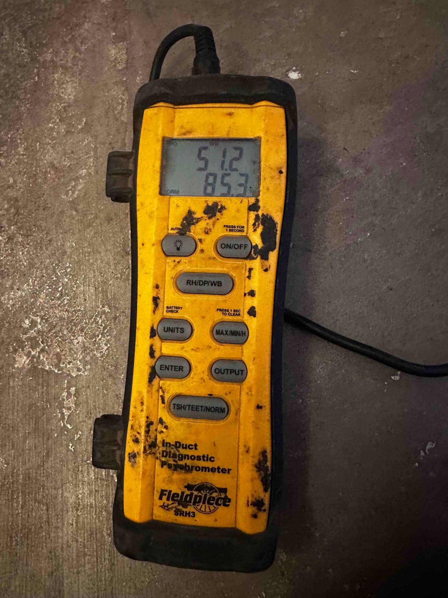 Digital thermometer displays 51.2°F, documenting cold supply air temperature during commissioning checks.