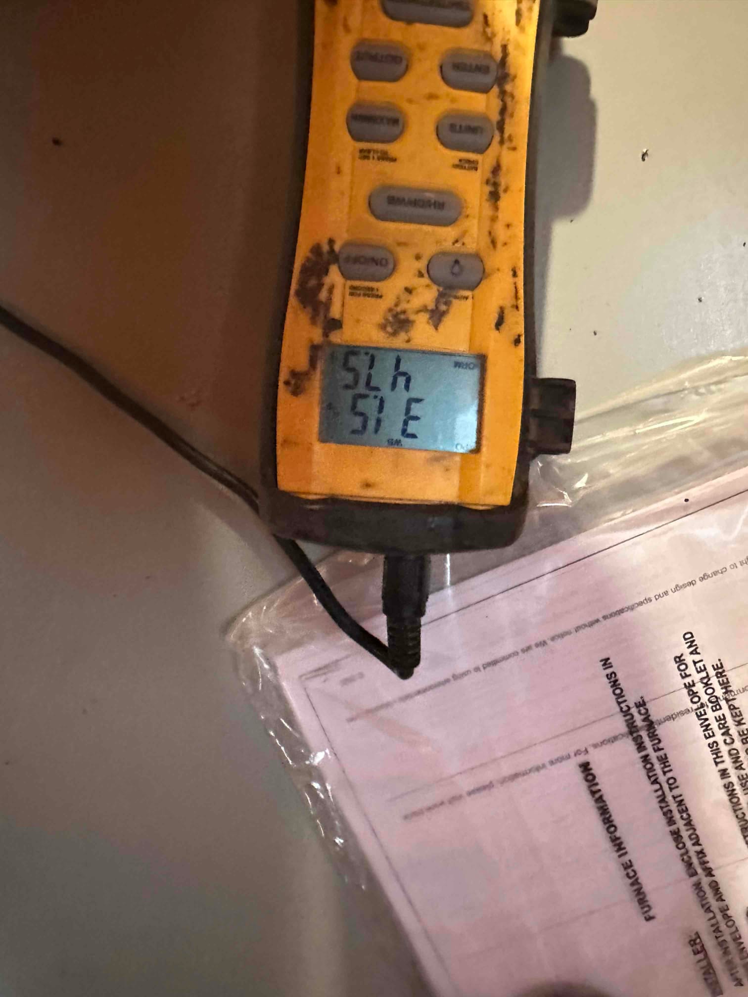 Digital thermometer displays 52 degrees, documenting supply air temperature at the outlet during system commissioning.