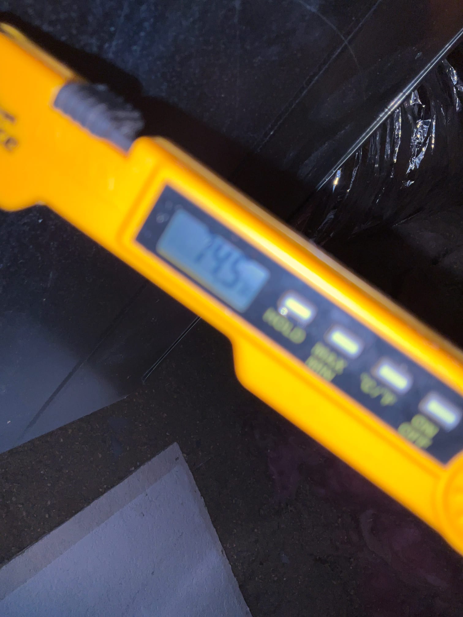Digital thermometer inserted at the air handler shows 74.5 degrees Fahrenheit, documenting return air temperature during commissioning.
