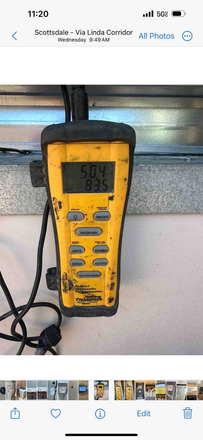 Digital thermometer measures air temperature at the duct, displaying 50.4°F supply air and 83.5°F return air during commissioning.