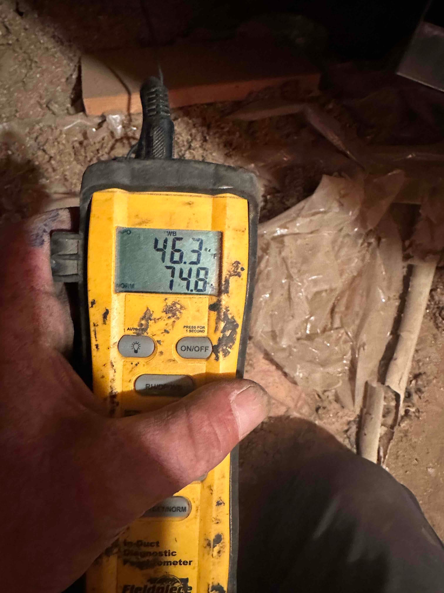 Digital thermometer probe shows 74.8 degrees in the return duct during airside commissioning of the new system.