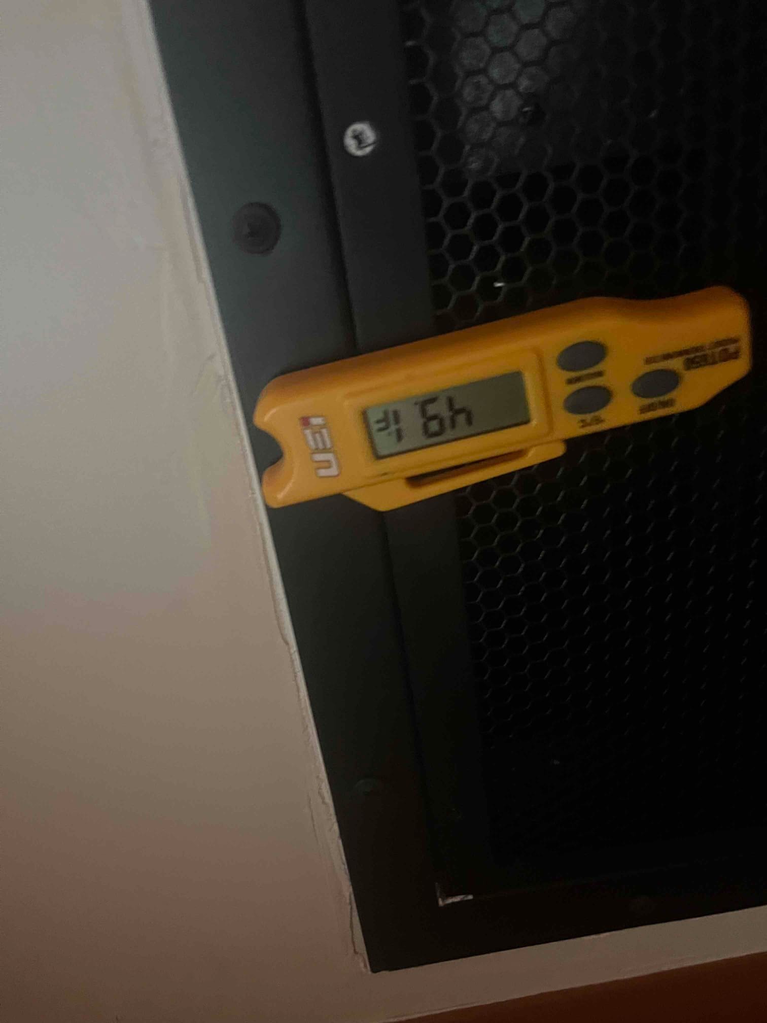 Digital thermometer at a return grille shows 79°F, documenting warm return air during system commissioning.