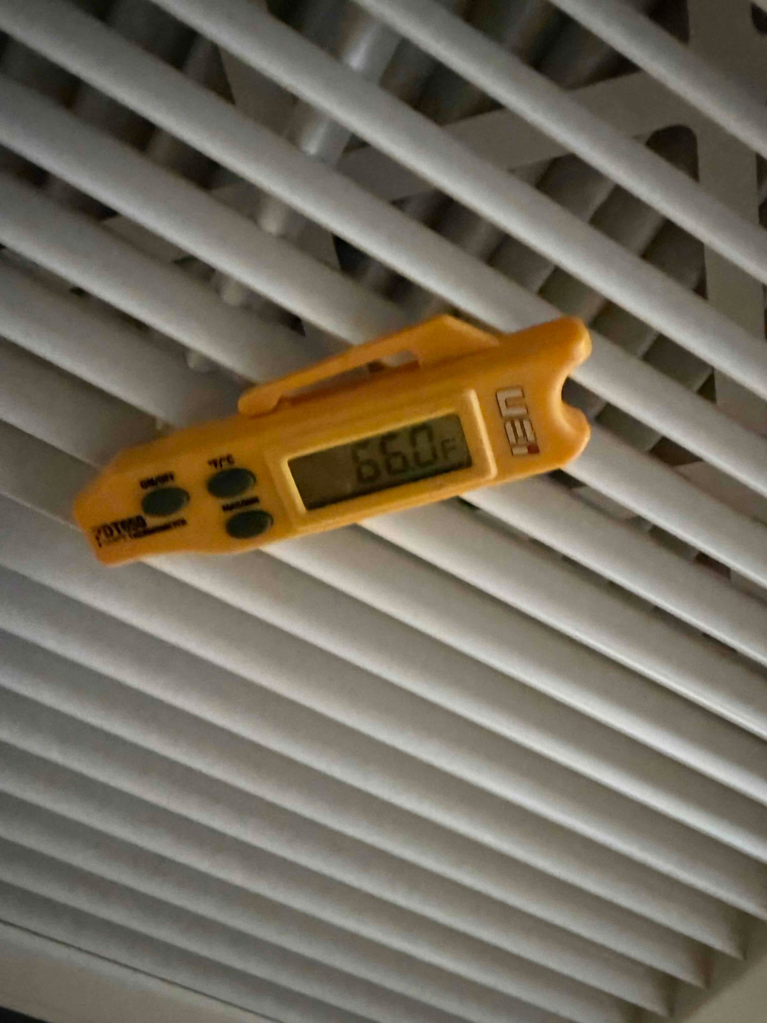 Digital thermometer at a supply register shows 66.0°F, documenting supply air temperature after system start-up.