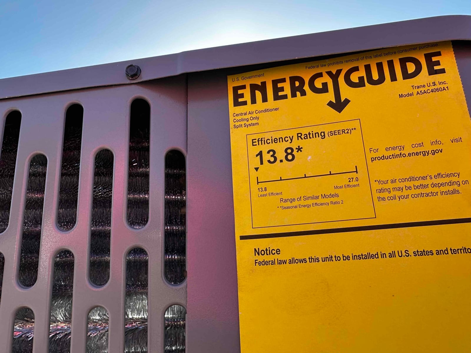 Energy efficiency label on a newly installed outdoor air conditioner cabinet, showing the coil through the grille.