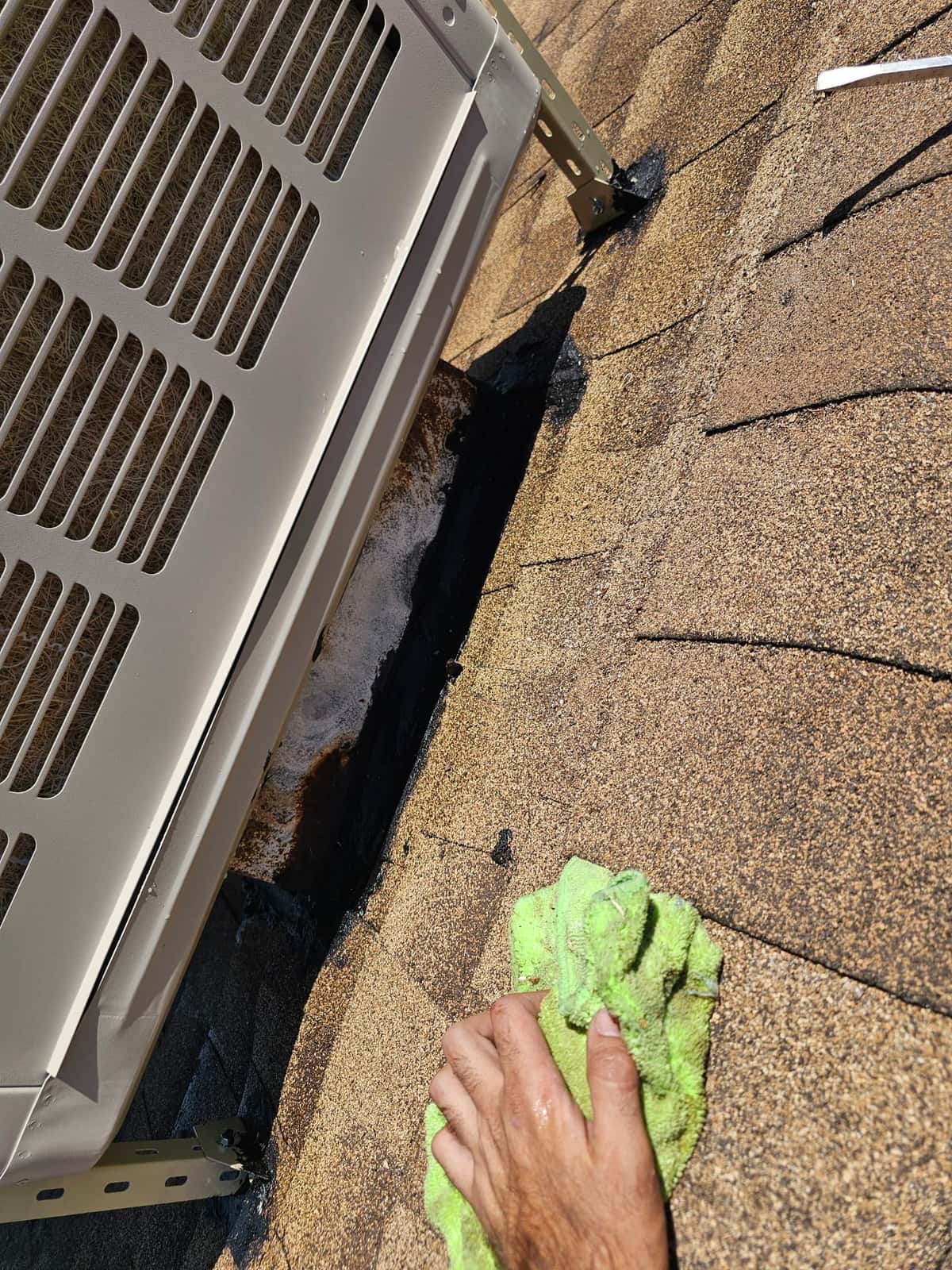 Evaporative cooler stand secured to roof with sealed mounting feet; technician wipes shingles and flashing around the penetrations.