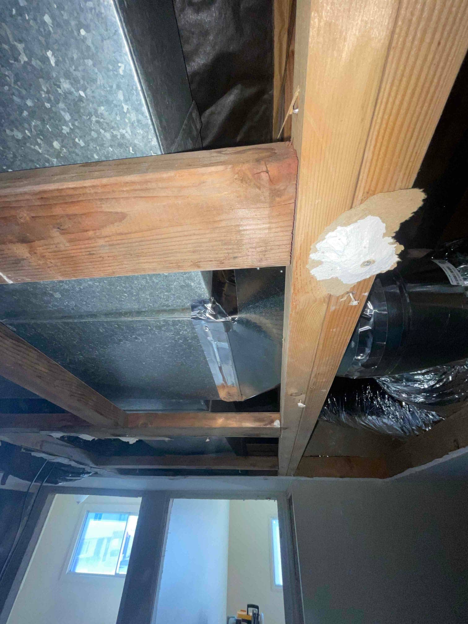 Exposed ceiling framing shows newly installed galvanized duct and insulated flexible branch duct routed through joist space.