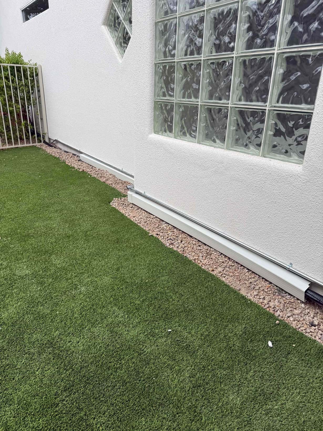 Exterior line set covers secured along the stucco wall above gravel border, routing refrigerant and control lines neatly to the mini‑split system.