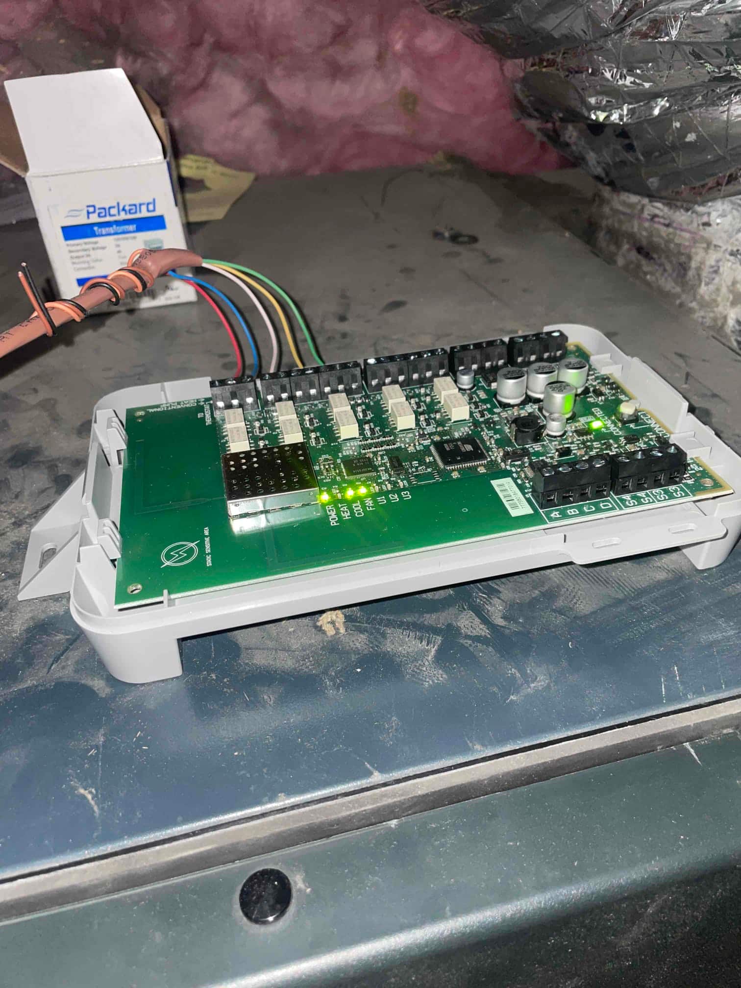 Furnace control board on the air handler cabinet with multiple connectors attached and green status LEDs illuminated.