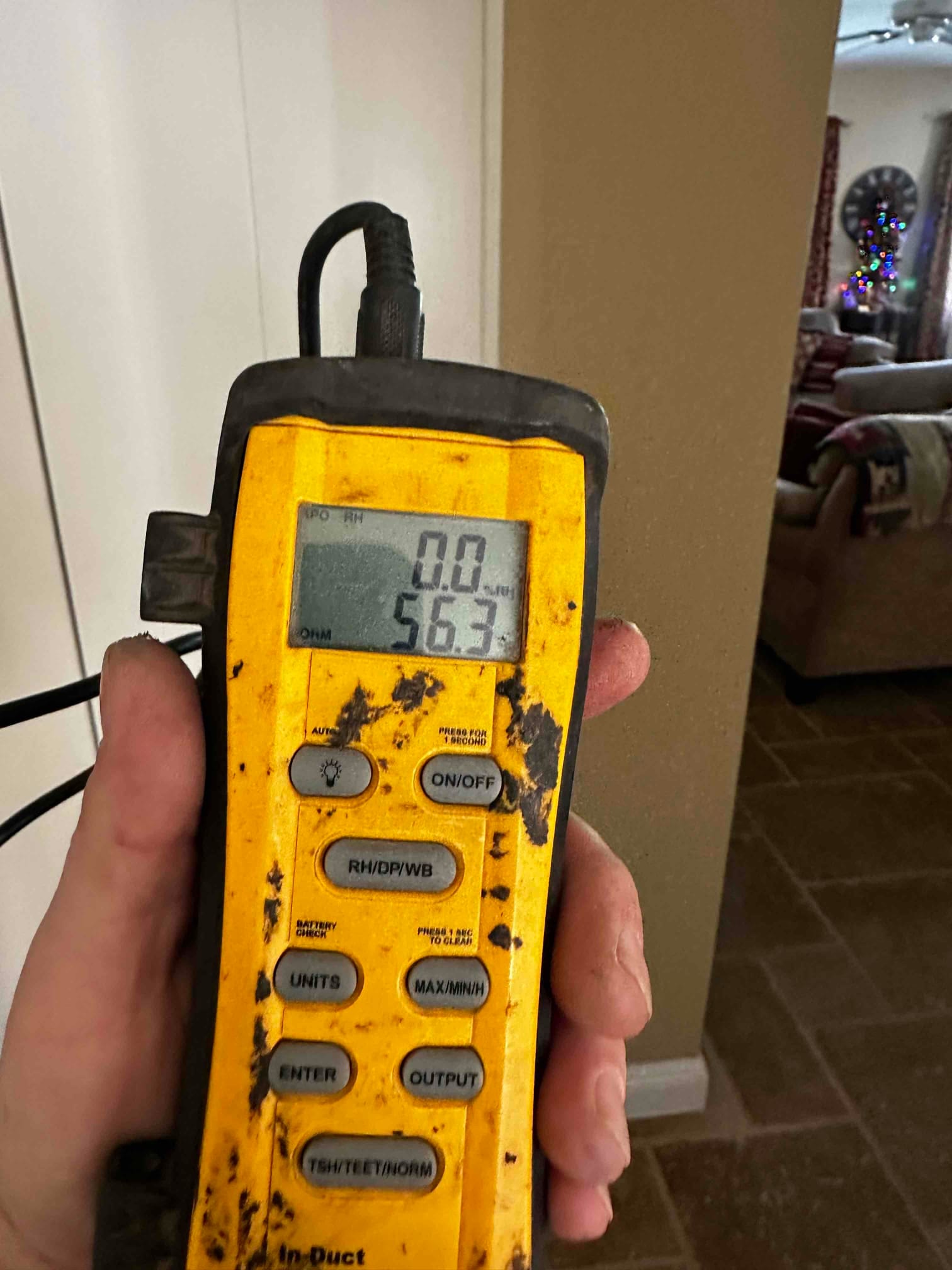 Handheld digital thermometer shows 56.3 degrees, documenting supply air temperature during system commissioning.