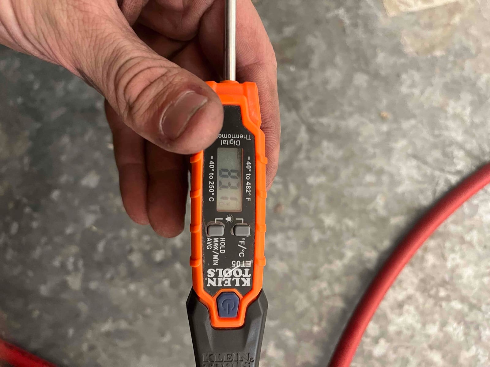 Handheld digital thermometer shows 60°F during air temperature check with probe inserted at the test location.