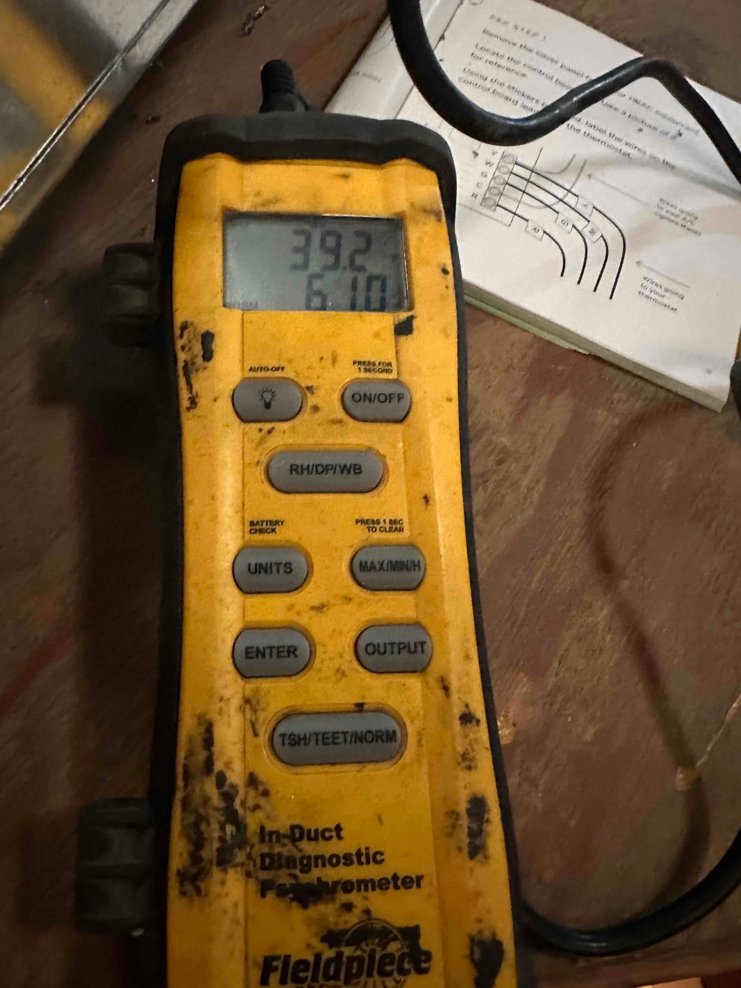 Handheld in-duct diagnostic meter displays 39.2 on the upper line and 6.10 on the lower line during airflow testing.
