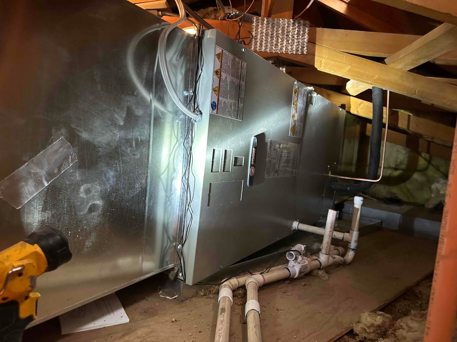 Horizontal air handler installed in attic with insulated refrigerant line and newly plumbed condensate drain with cleanout and trap.