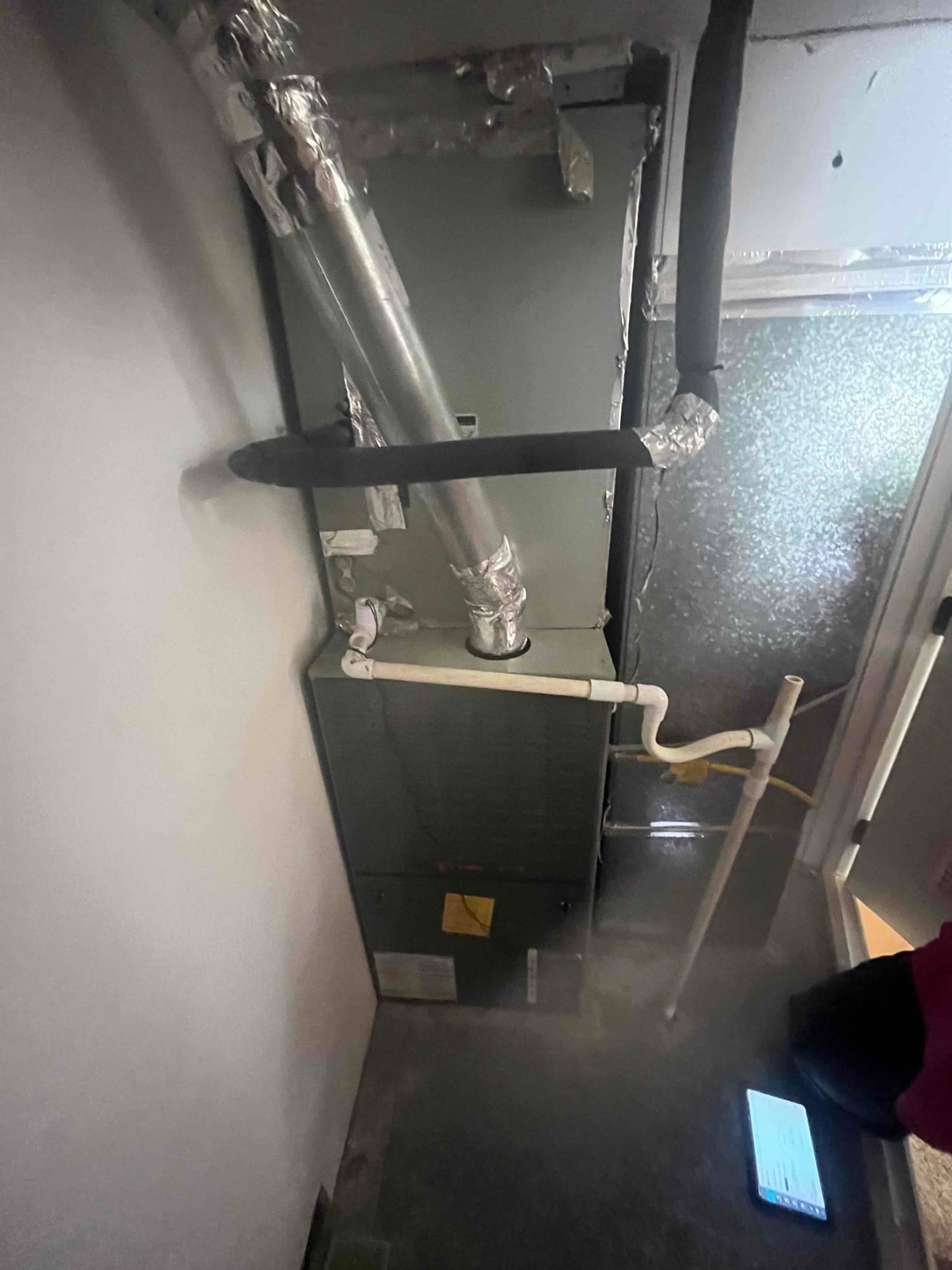Indoor air handler installed with insulated refrigerant lines, sealed duct connections, and condensate drain piping routed to trap and standpipe.