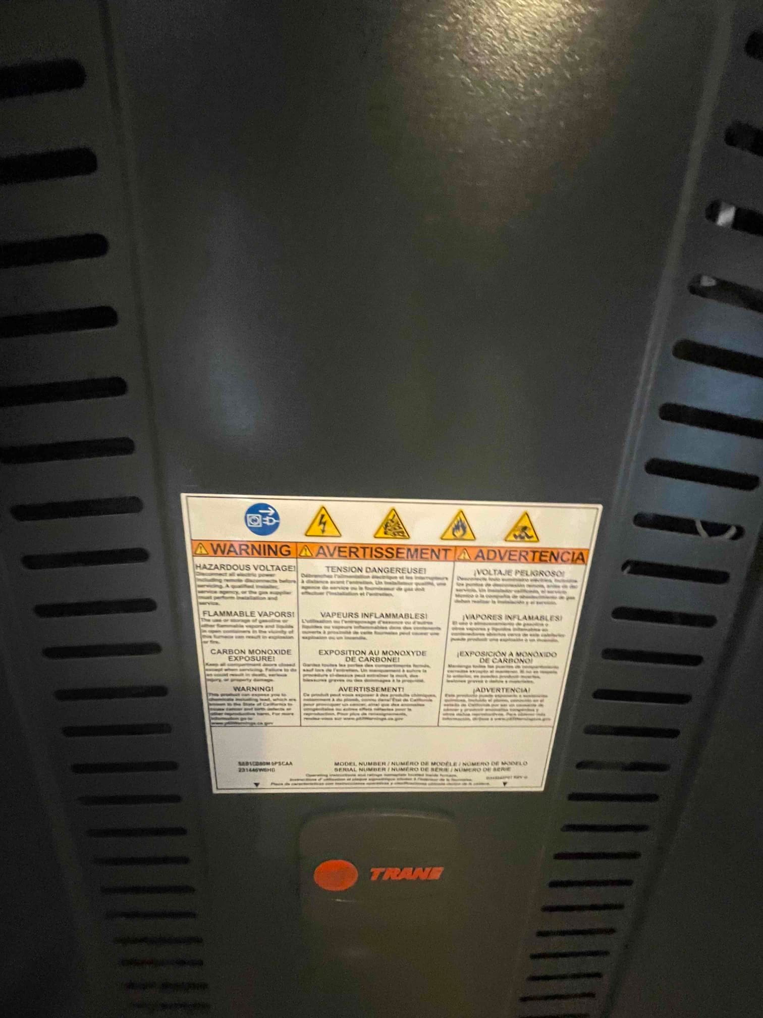 Indoor furnace cabinet with safety warning label visible on the front panel during a new HVAC installation.