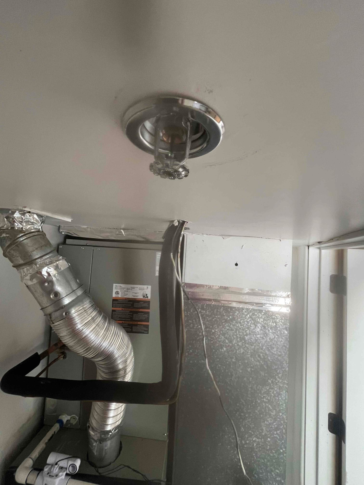 Installed gas furnace with venting, insulated refrigerant line, condensate drain, and sealed sheet metal plenum inside a utility closet.