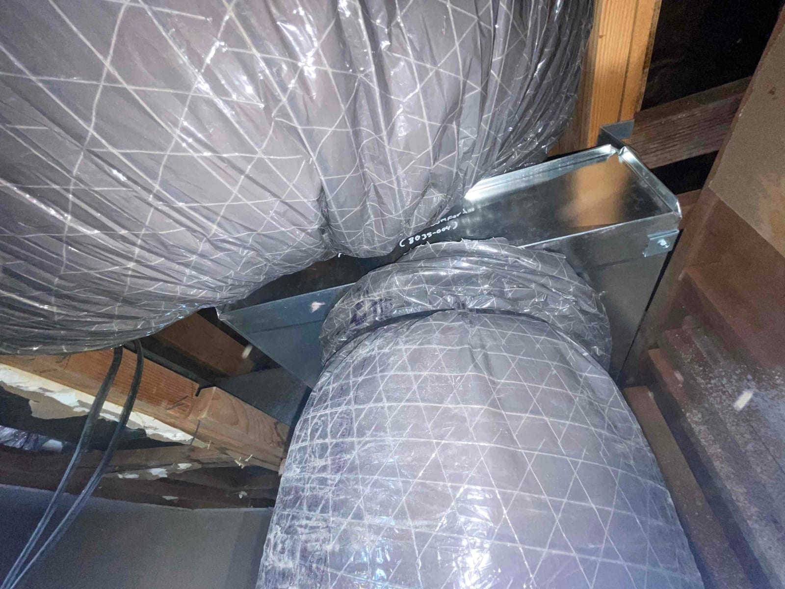 Insulated flexible ducts connected to a new galvanized metal plenum in the attic framing, showing completed airflow connections.