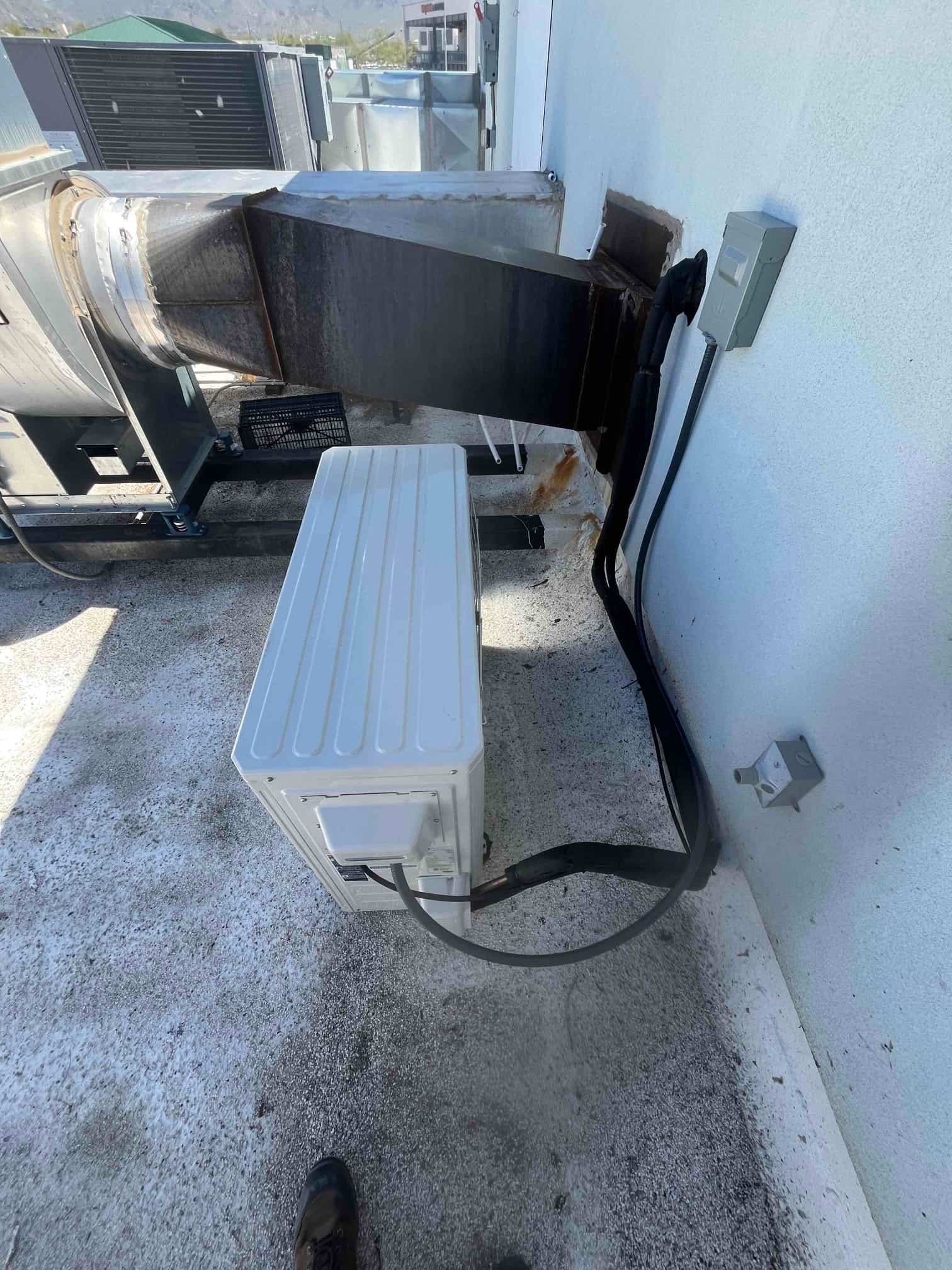 Mini-split outdoor unit set on rooftop with insulated line set, sealed wall penetration, and weatherproof electrical disconnect installed.