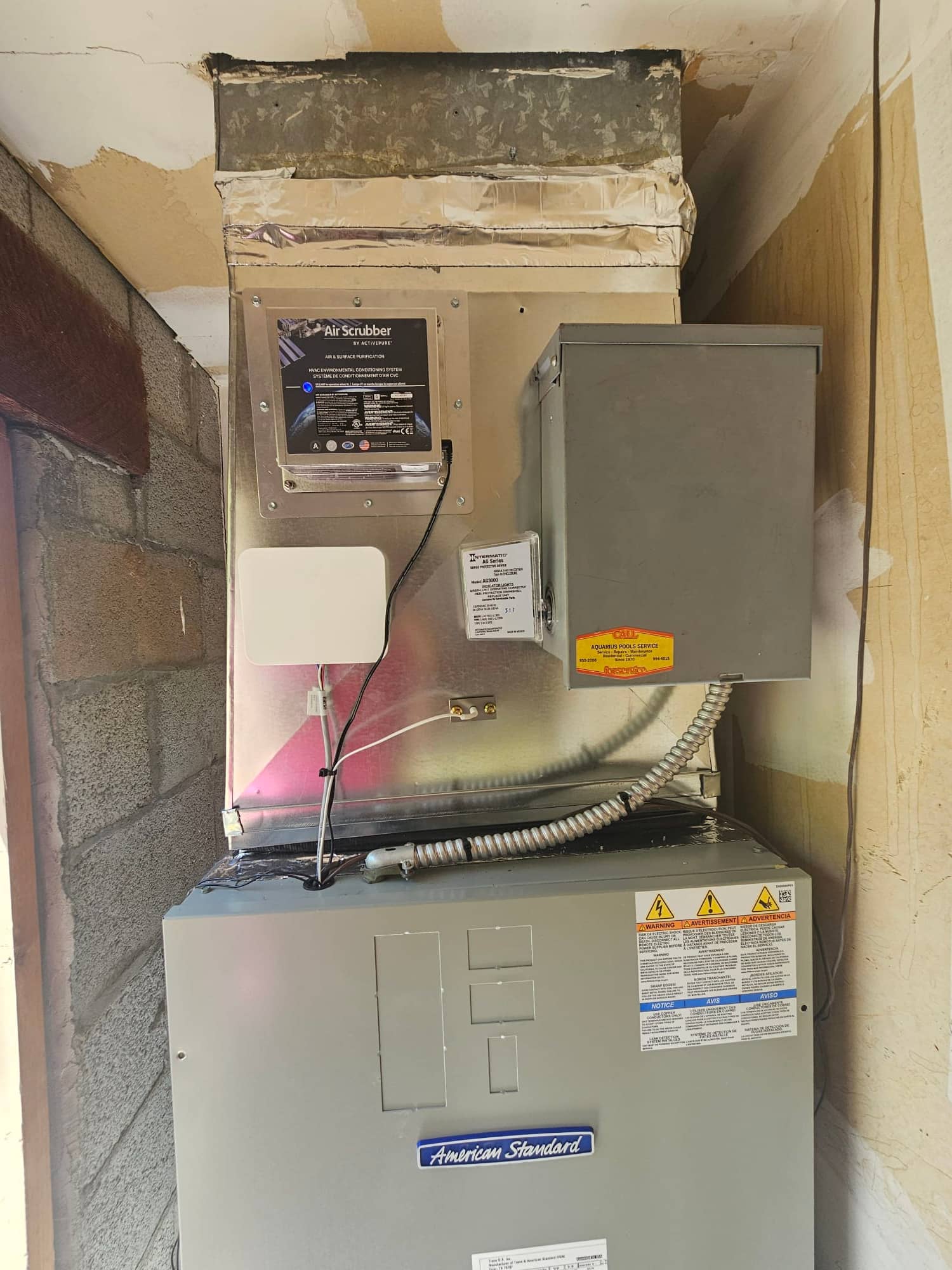 New air handler installed with sealed duct connection, inline air purification device, and mounted electrical disconnect with flexible conduit.