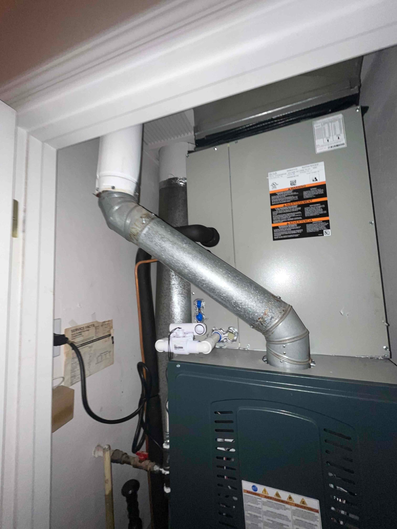 New furnace and coil installed in closet with PVC venting, galvanized flue, condensate trap, and insulated refrigerant line.