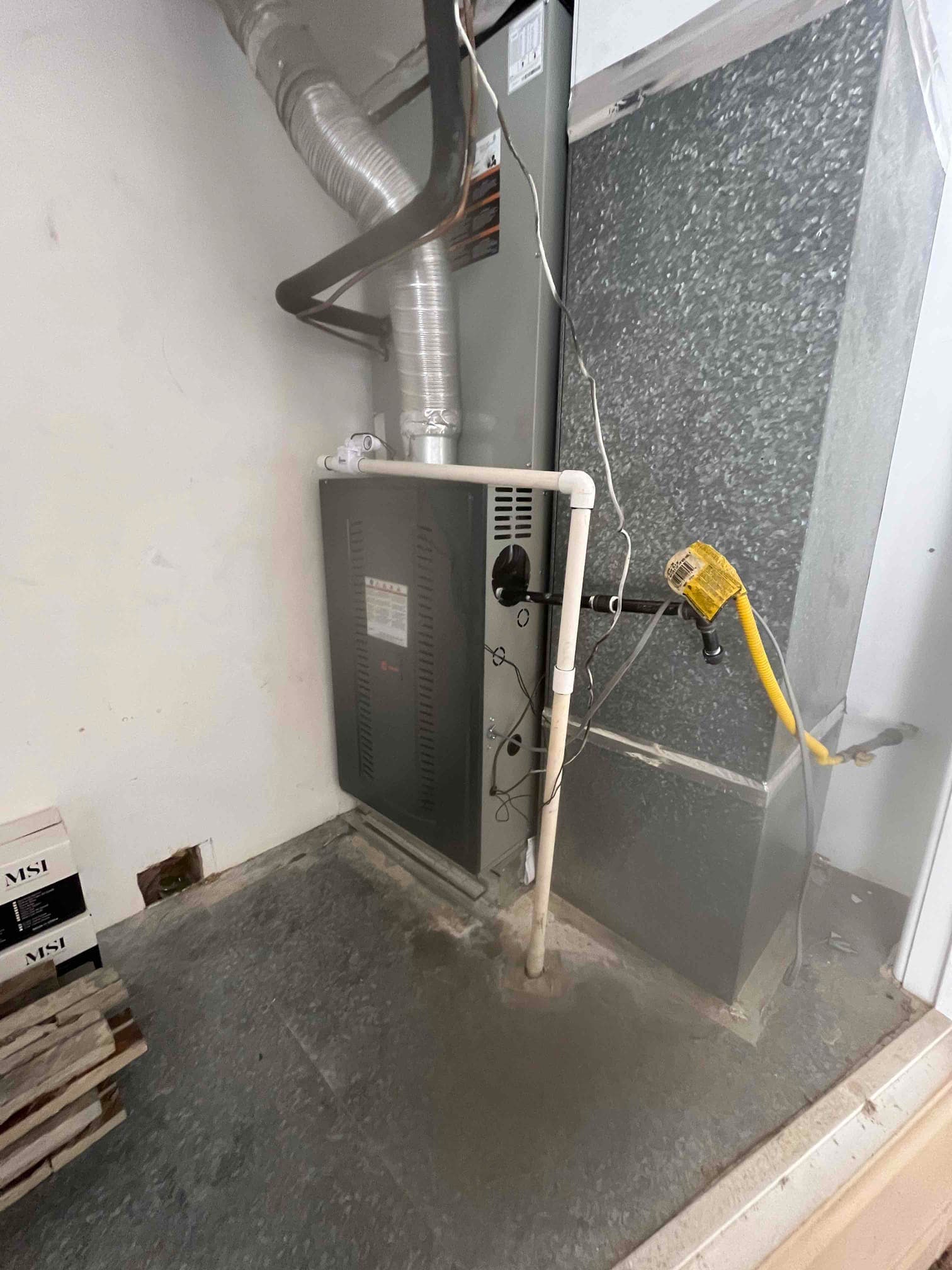 New furnace and evaporator coil set in closet with duct connections, condensate drain, gas flex line, and electrical whip routed.