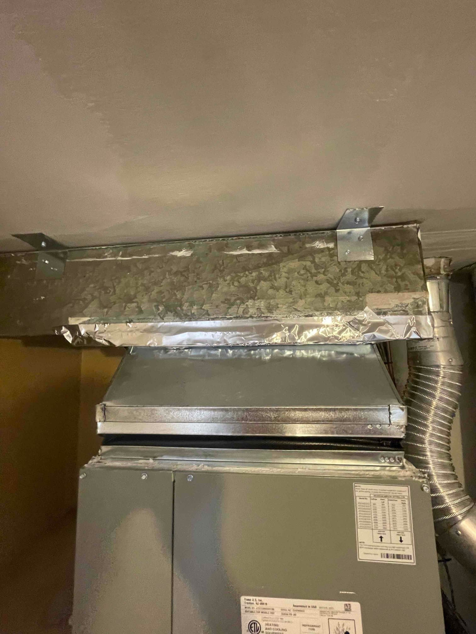 New furnace with transition to supply plenum, sealed with foil tape and supported by metal straps at the ceiling.