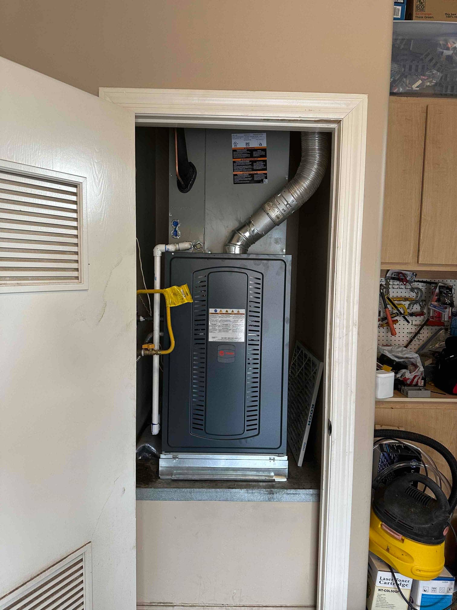 New gas furnace installed in a closet with venting, condensate drain, gas flex connector, and return filter access.